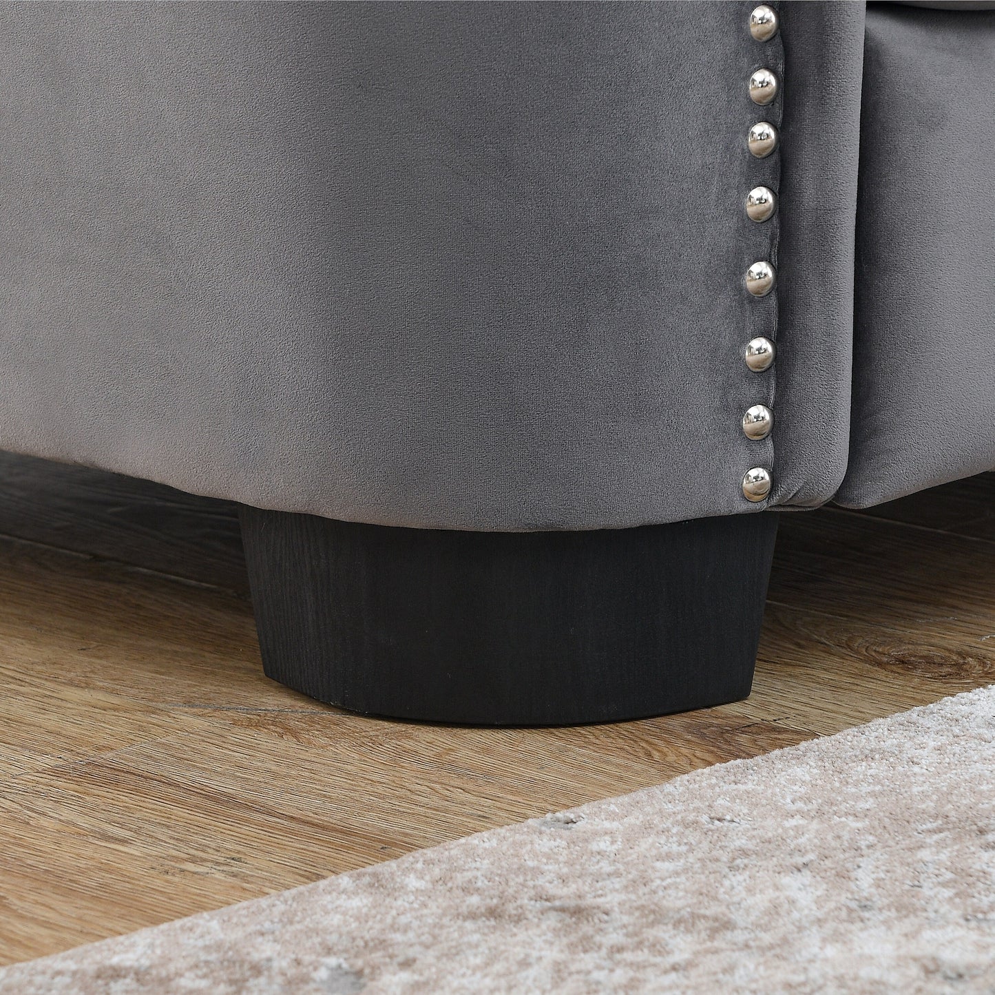 Canapé 2 places gris moderne en velours de 150 cm avec dossier capitonné et accoudoirs cloutés.